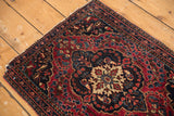 Antique Farahan Sarouk's scalloped medallion, cherry red and navy floral field, tattered corner.