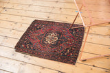 Antique Farahan Sarouk rug, cherry red, navy floral medallion, and worn edges.