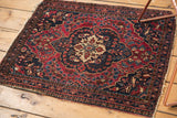 Antique Farahan Sarouk rug corner, cherry red field, navy floral border with edge wear.