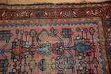 Detail of hand-knotted Lilihan rug: dusty rose field, blue shrimp motifs, and worn border.