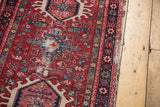 Close-up of vintage Karaja runner's classic geometric pattern, cherry red field, and exposed wear.