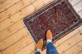 Vintage Lilihan rug upper right, raspberry red floral motif, blue border, worn fringe.