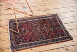 Lilihan rug corner showing floral bouquet motif, dark red ground, and tattered fringe.