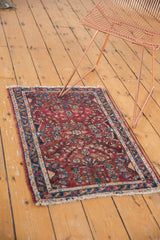Vintage Lilihan rug mat's bottom end with tattered fringe and red floral motif.