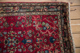 Intricate navy border and low pile texture on a vintage cherry red Lilihan rug corner.