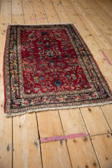 The complete vintage Lilihan rug showing its allover cherry red field and navy border from an angle.