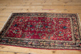 Angled view of a vintage Lilihan rug showing low pile, wear, and white knot speckling.