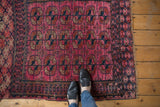 Fuchsia red field of an antique Turkmen rug, featuring triple elephant footprint guls in navy and rust.