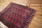 Geometric navy and fuchsia borders with tattered ends on the antique Turkmen rug.
