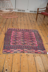 Antique Turkmen square rug with fuchsia elephant footprint guls, navy borders, and tattered ends.
