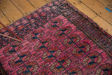 Close view of antique Turkmen rug's fuchsia field, elephant footprint guls, and tattered fringe.