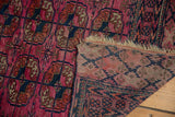 Antique Turkmen rug: low fuchsia pile, tattered fringe, blush elephant footprint on reverse.