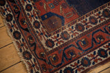 Antique Afshar rug corner: contrasting geometric borders in red, blue, with light tattered fringe.