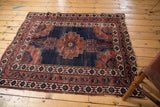 Antique Afshar rug corner with detailed wine red, navy, and ivory borders, showing light tatter.
