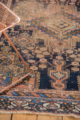Antique Afshar rug's hand-knotted geometric field with navy, apricot, and sky blue motifs, plus fringe.
