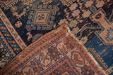 Antique Afshar rug's folded corner reveals navy geometric field and tattered ends.