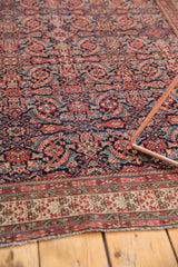 Angled view of an antique Malayer rug's dense herati pattern and ivory-ground border.