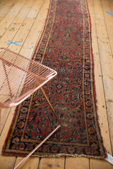 Black cherry red Lilihan runner with dense navy floral motifs and visibly tattered edge.
