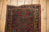 Tattered edge of a vintage Lilihan rug showing black cherry red field and floral pattern.