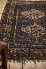 Vintage Qashqai rug with navy field, hook-and-latch pattern, geometric borders, worn fringe.