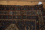 Vintage Qashqai rug's geometric border featuring hook-and-latch motifs in deep navy and mallard green.