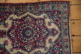 Corner of an antique Kermanshah rug showing the intricate floral borders and worn side cord selvage.