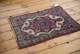 Angled perspective on an antique Kermanshah rug, highlighting its low pile and overall even wear.