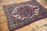 Antique Persian Kermanshah rug viewed from an angle, displaying its even, low-pile texture and floral design.