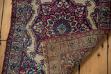 Antique Persian Kermanshah rug corner folded back, revealing the detailed hand-knotted weave on the reverse.