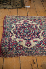 Antique Kermanshah mat showing its traditional design and aged patina from an angled view.