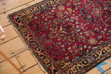 Vintage Lilihan rug corner with dark red floral field, patterned border, and tattered edge.