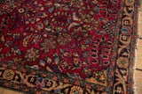 Corner detail of Vintage Lilihan rug, with black cherry red floral motifs and worn border fringe.