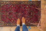 Lilihan rug's dark red field, allover vinery pattern, low pile, and tattered fringe end.