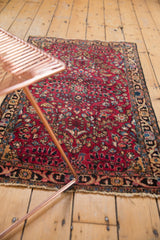 Vintage Persian Lilihan rug pattern with black cherry red floral field and tattered fringe.