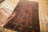 Low pile on an Antique Lilihan rug, showcasing dusty raspberry field, teal medallion, and worn side edge.