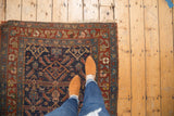 Antique Kurdish Hamadan rug corner, indigo field, madder red border, Herati motifs, tattered edges.