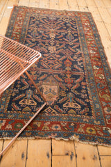 Antique Kurdish Hamadan rug's lower section with indigo field, geometric vase motif, and tattered red fringe.