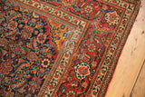 Intricate Herati pattern in indigo, madder red, and ivory on an antique Fereghan rug's corner.