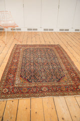 Corner detail of an antique Persian Fereghan rug, highlighting its intricate Herati motif, madder red border, and fringe.
