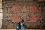 Antique Malayer rug corner detail: faded field, worn navy herati spandrel, and tattered fringe.