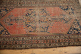 Pinwheel floral main border and vine motifs on a faded brick red antique Kurdish Malayer rug.