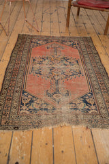 Bottom corner of an antique Kurdish Malayer rug, showing worn fringe and pinwheel floral border.