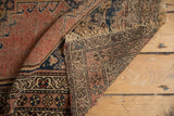 Folded antique Kurdish Malayer rug revealing worn pile, woven back, and fringe.