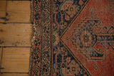 Worn selvage edge, vine motif border, and faded brick red field on an antique Kurdish Malayer rug.