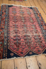 Antique Lilihan rug corner detail: faded raspberry field, germinating plant motifs, navy border.