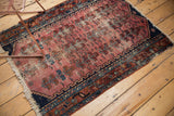Antique Lilihan rug side detail, tattered edge, worn faded raspberry field, navy, copper tones.