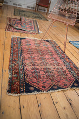 Antique Lilihan Fragment rug corner detail: faded raspberry field, navy border, plant and fish motifs.