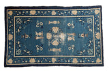 Antique Chinese Peking rug, denim blue field, ivory floral medallion, urns, and Taoist motifs.
