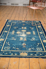 Antique Peking rug field with denim blue and ivory symbolic urn motifs, showing concentrated wear.