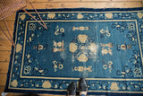 Antique Peking rug corner detail: denim blue field, ivory urns, Taoist imagery, mostly even wear.